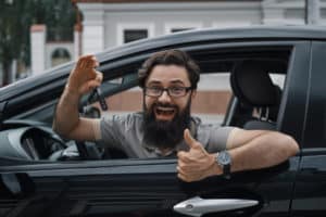man holding car keys showing thumbs up for his car dent repair
