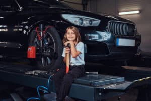 little girl sitting beside a car under maintenance to protect your car