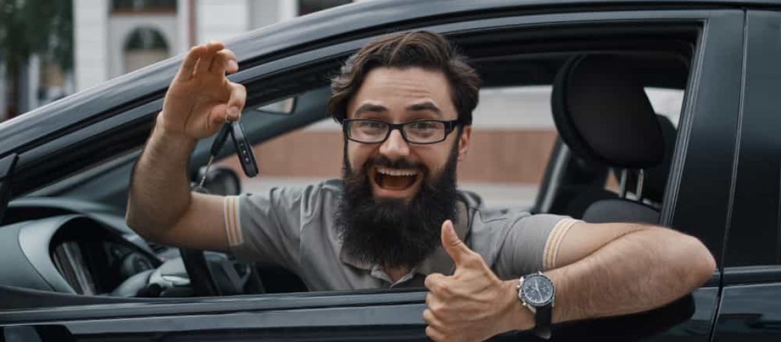 man holding car keys showing thumbs up for his car dent repair