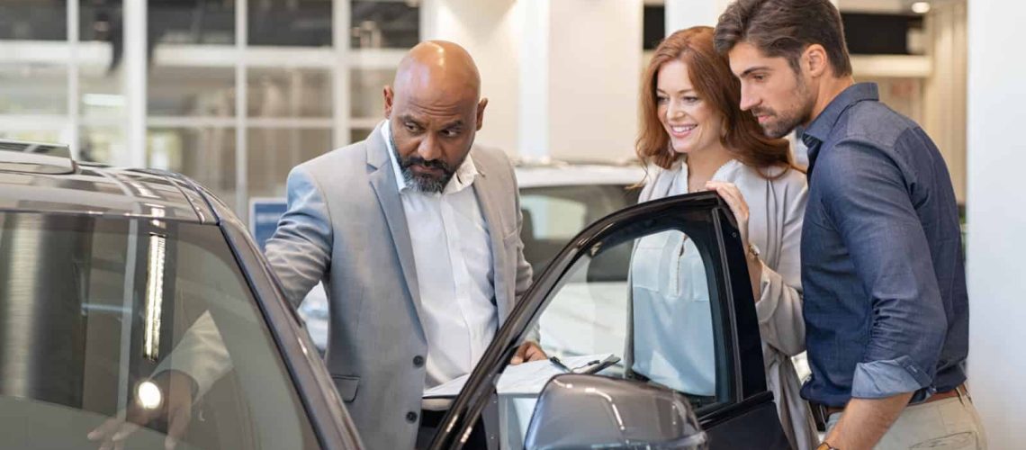 Salesman showing car features to a couple